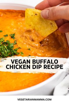 a hand dipping a tortilla chip into a bowl of vegan buffalo chicken dip