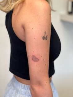 a woman with a small tattoo on her left arm and two cherries in the middle