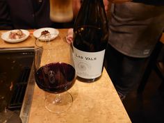 a glass of wine sitting on top of a counter next to a bottle of wine