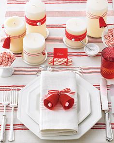 the table is set with red and white dishes, silverware, candy canes and candles