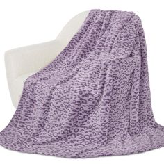 a purple leopard print blanket sitting on top of a white chair