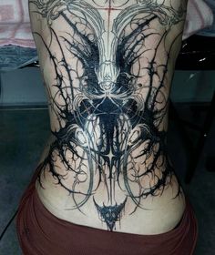 the back of a woman's body is covered in black ink and intricate designs