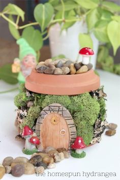 a potted plant with a mushroom house on top of it and rocks around it