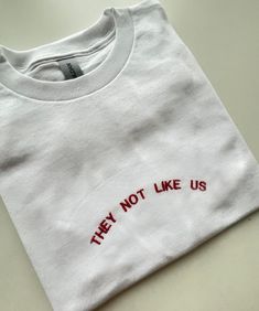 They Not Like Us, Embroidered T-shirt, Monogram, Funny T-shirt, Unisex, SHIPPING INFO: FREE UK DELIVERY are sent as 1st Class (1-2 Working days) UK EXPRESS (Next day delivery) this is an extra cost at checkout Europe sent as International Tracked (Expected 3-5 working days) Worldwide sent as International Tracked (Expected 5-7 working days) EMBROIDERY THREAD: POLYESTER T-SHIRT: 100% COTTON (WHITE 170 GSM) (OTHER COLS 180 GSM) SWEATSHIRT: 80% COTTON, 20% POLYESTER (WHITE + HEATHER GREY 260 GSM) ( Basic Crew Neck Tops With Embroidered Logo, White Crew Neck T-shirt With Embroidered Logo, Cotton T-shirt With Embroidered Graphics, Crew Neck, Crew Neck Top With Embroidered Logo In Relaxed Fit, Tan Crew Neck T-shirt With Screen Print, Graphic Tee With Embroidered Logo And Short Sleeves, Cotton T-shirt With Embroidered Graphics, Short Sleeve Cotton Tops With Embroidered Logo, Cotton Crew Neck T-shirt With Text Print