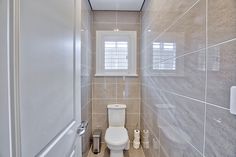 a white toilet sitting inside of a bathroom next to a wall mounted heater under a window