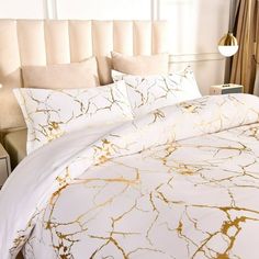 a bed with white and gold comforters in a bedroom