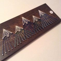 a wooden board with pins arranged in the shape of trees on it, sitting on a table