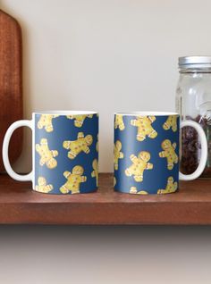 two mugs sitting on top of a wooden shelf next to a jar filled with cookies