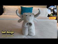 a stuffed cow is sitting on a bed with the name cow in front of it