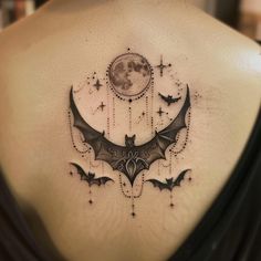 a bat tattoo on the back of a woman's upper back and shoulder, with bats flying around it