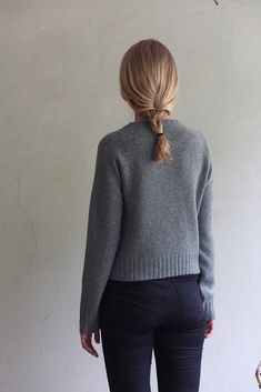 a woman standing in front of a white wall with her back turned to the camera