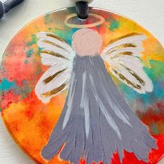 a painted angel ornament sitting on top of a piece of paper next to a crayon marker