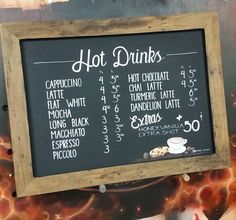 a menu for hot drinks on a chalkboard in front of a fire and flames background