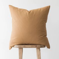 a tan pillow sitting on top of a wooden chair