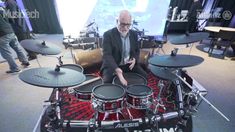 a man sitting on top of a drum set in front of a projector screen