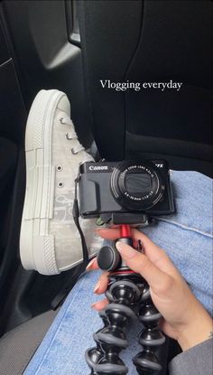 a person holding a camera in their hand while sitting on a car seat with the words vlogging every day