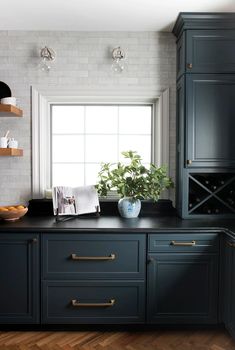 a kitchen with dark blue cabinets and wood flooring is pictured in this image, there are shelves on either side of the window