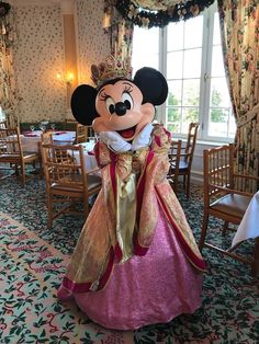 a person dressed up in a princess costume at a dining room table with chairs and tables