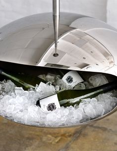 two bottles of wine sitting in ice on top of a metal bowl filled with water