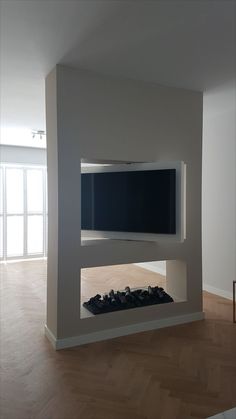 an empty room with a television mounted on the wall and wood flooring in front of it