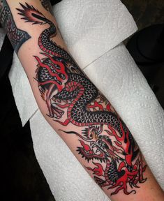 a man's arm with a dragon tattoo on it and red flames in the background