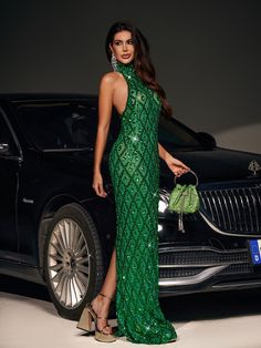 a woman in a green dress standing next to a car