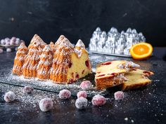 a cake with powdered sugar on top and an orange in the background next to it