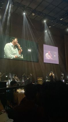 a man is singing on stage in front of a crowd with lights and sound equipment