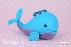 a blue and purple whale toy sitting on top of a pink table