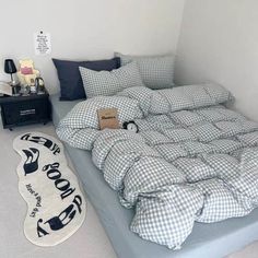 an unmade bed with blue and white checkered comforter in a small room