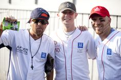 three men in baseball uniforms are posing for a photo with one man holding a drink