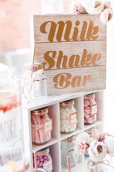 a wooden sign that says milk shake bar on top of a shelf filled with candy