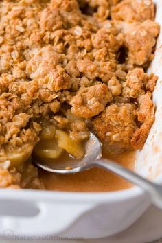 a close up of a spoon in a casserole dish filled with apple crisp