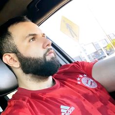 a man with a beard sitting in the passenger seat of a car and looking up