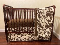 a brown and white crib bedding set with flowers on the side, next to a hardwood floor