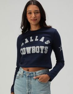 Dallas Cowboys Long Sleeve Baby Tee. Show Your Team Pride With This Dallas Cowboys Long Sleeve Baby Tee. Featuring "dallas Cowboys" Screened Across The Front Chest And A Bold Star Graphic On The Left Sleeve, This Fitted Tee Is Perfect For Fans Looking For A Stylish And Sporty Look. Ideal For Game Day Or Casual Wear! 94% Cotton, 6% Spandex. Machine Wash. Imported. Model Is Wearing A Size Small. Model Measurements:height: 5'8" Bust: 32"waist: 24"hips: 35" Collegiate Letter Print Tops For Fall, Blue Tops For Fall Game Day, Fitted Letter Print Tops For Fans, Collegiate Style Tops With Text Print For Spring, Collegiate Style Text Print Tops For Spring, Spring Game Day Top With Text Print, Blue Fitted Top For Game Day, Blue School Spirit Tops For Fall, Blue Tops For Fall School Spirit