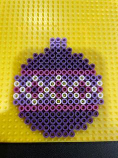 a purple and white object made out of legos on a yellow surface with circles