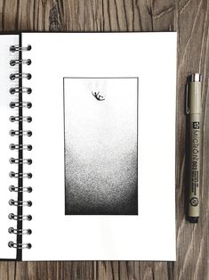 an open notebook with a black and white photo on the cover next to a pen