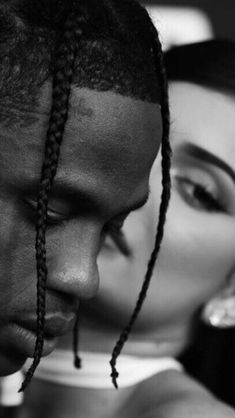 a man with dreadlocks is kissing a woman's face in black and white