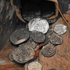 a pile of old coins sitting on top of a fur covered floor next to a bag