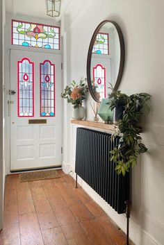 a room with a radiator, potted plants and a mirror on the wall