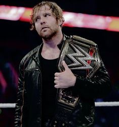 a man in a leather jacket holding a wrestling belt