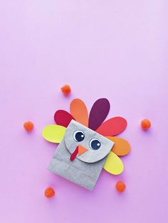 a paper bag with a turkey on it and some pom poms around it