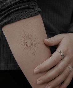 a woman's arm with a small sun tattoo on the left side of her arm