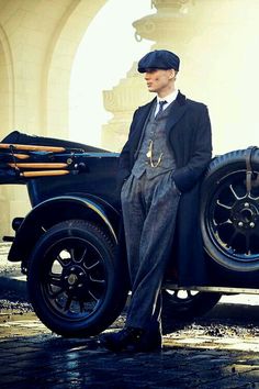 an old photo of a man standing next to a car