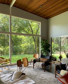 a living room filled with lots of furniture and large windows overlooking a lush green park