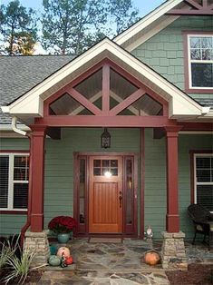 a green house with red trim and wooden front door, surrounded by stone steps leading up to it's entrance