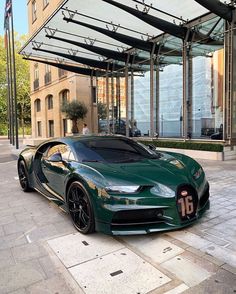 a green sports car parked in front of a tall building on a city street with an awning over it