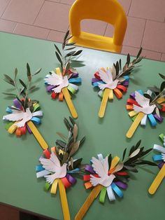 paper flowers are arranged in the shape of an umbrella on a green table next to a yellow plastic chair