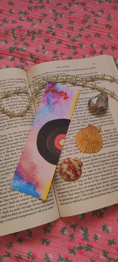 an open book on a pink table cloth with shells and seashells attached to it